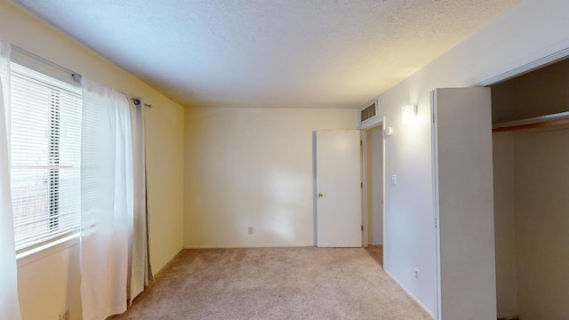 unfurnished bedroom with light carpet, a closet, and a textured ceiling