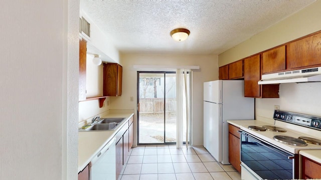 kitchen with sink, light tile patterned floors, a textured ceiling, and white appliances