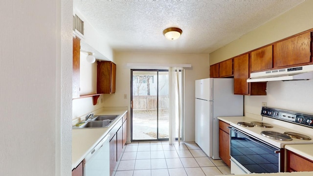 kitchen featuring sink, light tile patterned floors, a textured ceiling, and white appliances