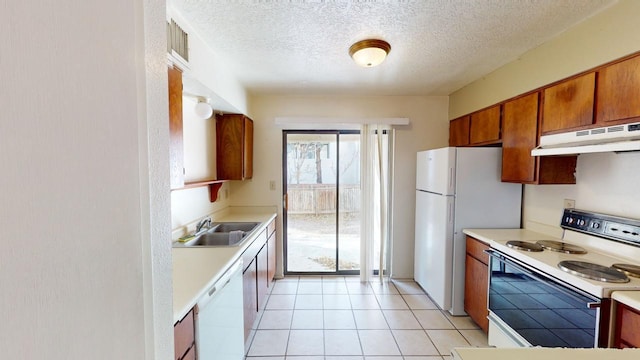 kitchen featuring white appliances, sink, a textured ceiling, and light tile patterned floors