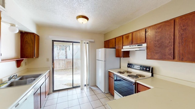 kitchen with white appliances, sink, a textured ceiling, and light tile patterned floors