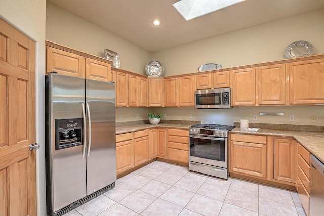 kitchen with light tile patterned floors, a skylight, and appliances with stainless steel finishes