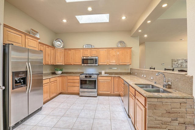 kitchen with sink, a skylight, light tile patterned floors, kitchen peninsula, and stainless steel appliances