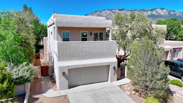 adobe home featuring a mountain view, a garage, and a balcony