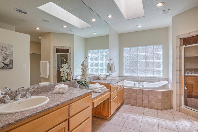 bathroom featuring plus walk in shower, a skylight, vanity, tile patterned floors, and a textured ceiling