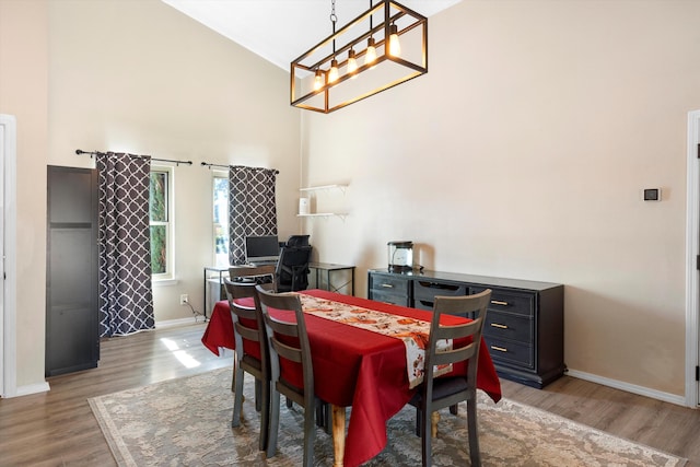 dining area with vaulted ceiling, hardwood / wood-style floors, and a notable chandelier