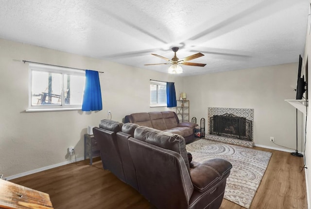 living room with hardwood / wood-style flooring, a wealth of natural light, a tile fireplace, and a textured ceiling