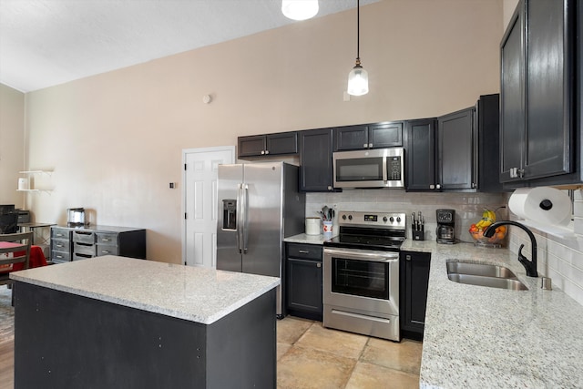 kitchen with stainless steel appliances, light stone countertops, sink, and decorative light fixtures