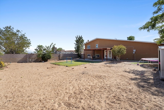 back of house with a trampoline and a patio area