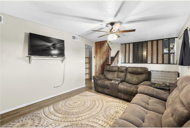 living room featuring hardwood / wood-style flooring, ceiling fan, and a textured ceiling