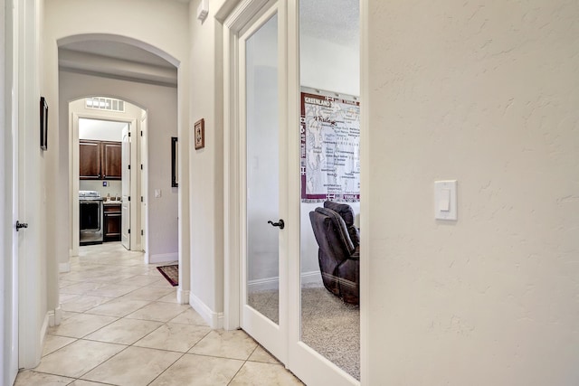 corridor featuring french doors and light tile patterned floors