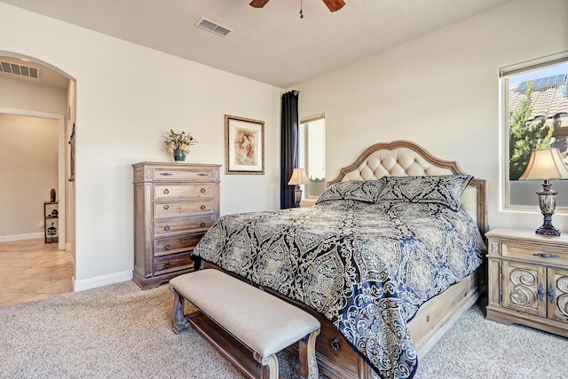 bedroom with ceiling fan, light carpet, and a textured ceiling