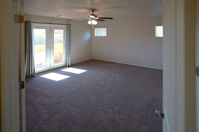 spare room featuring ceiling fan, dark carpet, a textured ceiling, and a wealth of natural light