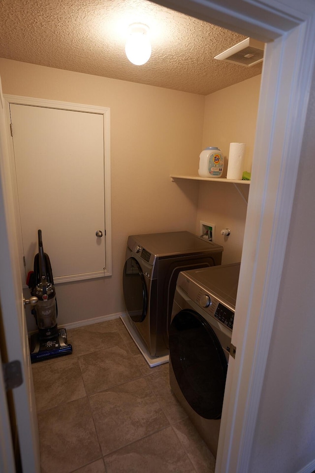 washroom with washer and dryer and a textured ceiling