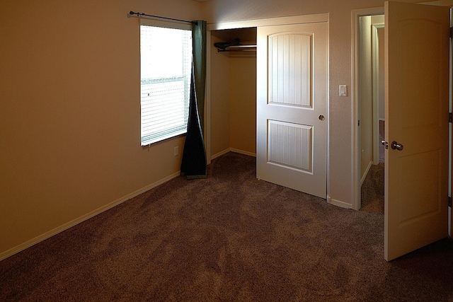 unfurnished bedroom with dark colored carpet and a closet