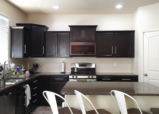 kitchen featuring backsplash, appliances with stainless steel finishes, sink, and dark stone counters