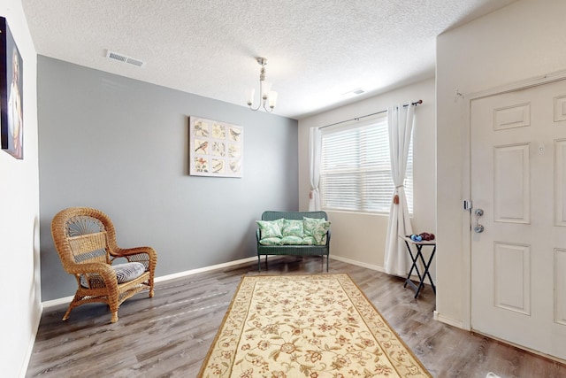 sitting room with a chandelier, a textured ceiling, and light wood-type flooring