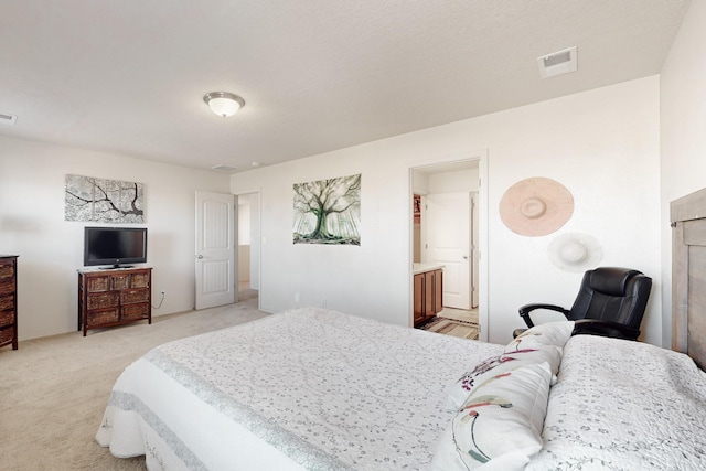 bedroom with light colored carpet and ensuite bath