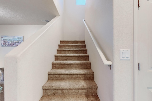 staircase featuring a textured ceiling