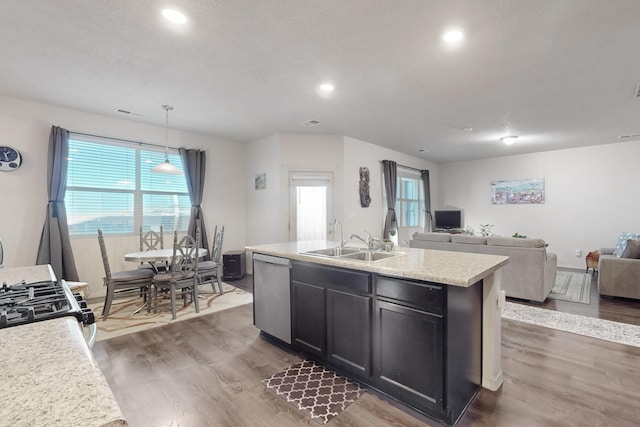 kitchen featuring dark wood-type flooring, sink, hanging light fixtures, a center island with sink, and appliances with stainless steel finishes