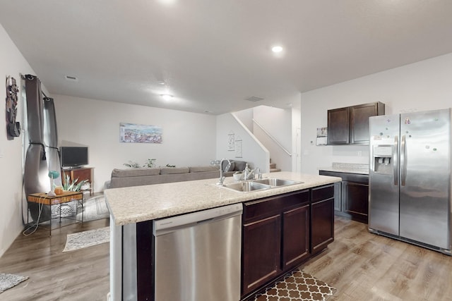 kitchen featuring sink, a kitchen island with sink, dark brown cabinets, stainless steel appliances, and light hardwood / wood-style floors