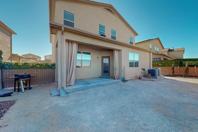 rear view of house with central AC and a patio area