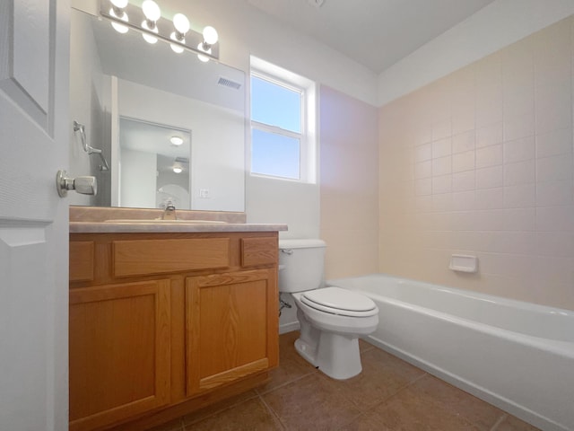 full bathroom featuring tile patterned flooring, vanity, tiled shower / bath, and toilet