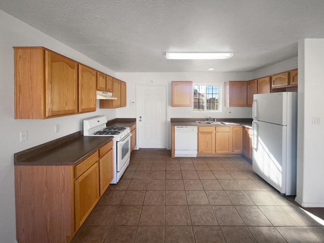 kitchen with tile patterned floors, sink, a textured ceiling, and white appliances