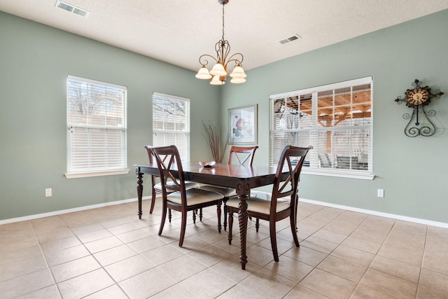 tiled dining area featuring a notable chandelier and a textured ceiling