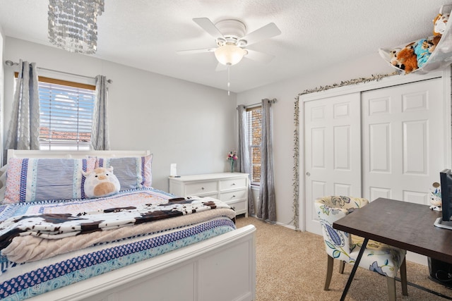 bedroom featuring ceiling fan, light carpet, a closet, and a textured ceiling