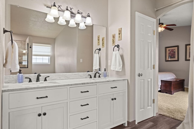 bathroom featuring ceiling fan, vanity, hardwood / wood-style floors, and a textured ceiling