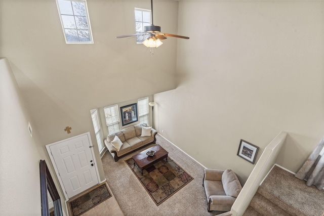 carpeted living room with ceiling fan and a high ceiling