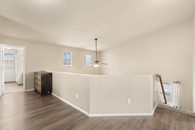 unfurnished room featuring a healthy amount of sunlight, hardwood / wood-style floors, a textured ceiling, and ceiling fan