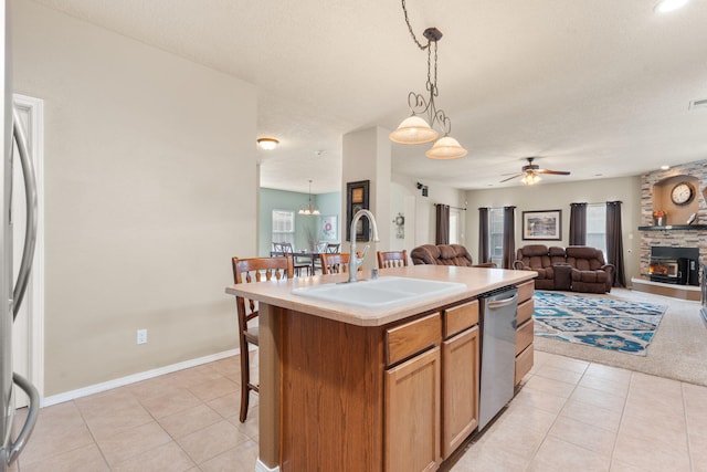 kitchen featuring sink, appliances with stainless steel finishes, hanging light fixtures, an island with sink, and light tile patterned flooring