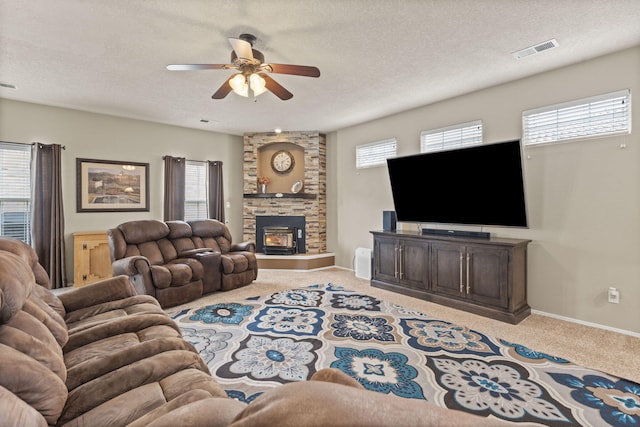 living room featuring a healthy amount of sunlight, light carpet, a fireplace, and a textured ceiling