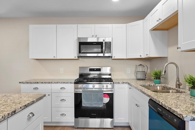 kitchen with white cabinetry, appliances with stainless steel finishes, sink, and light stone counters