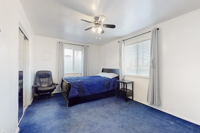 bedroom featuring ceiling fan, dark carpet, and multiple windows