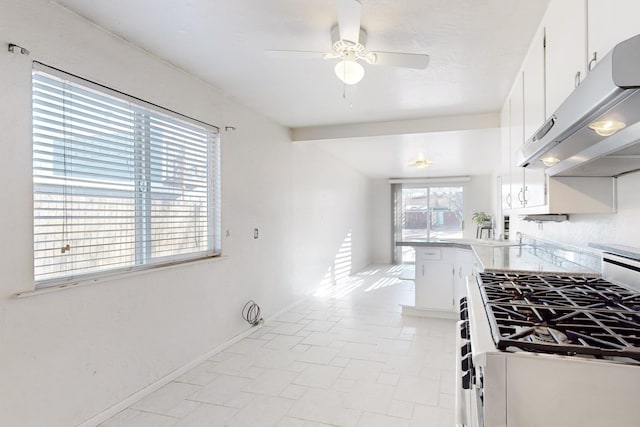 kitchen with stainless steel gas range, ceiling fan, white cabinets, kitchen peninsula, and beamed ceiling