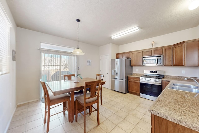 kitchen featuring decorative light fixtures, sink, light tile patterned floors, stainless steel appliances, and a textured ceiling