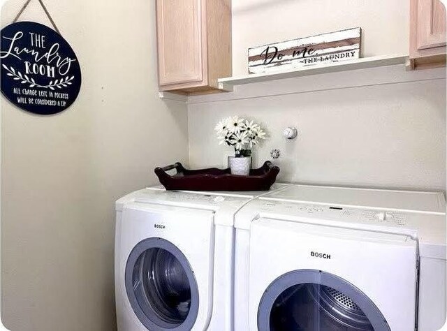 washroom with cabinets and washing machine and clothes dryer