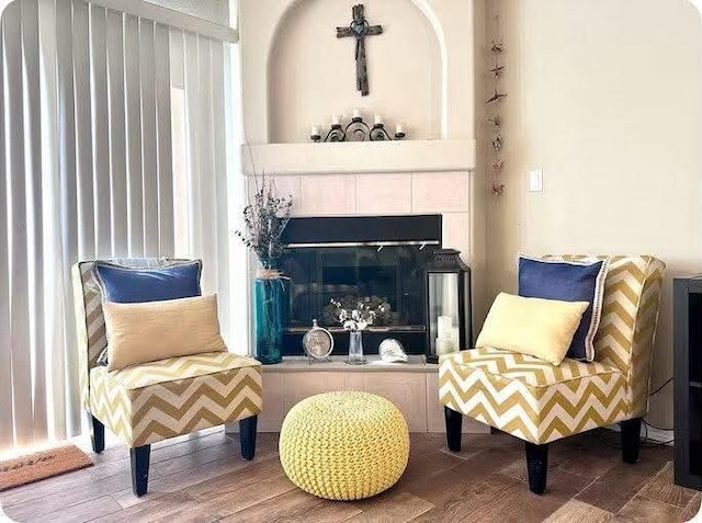 living area with a tile fireplace and wood-type flooring