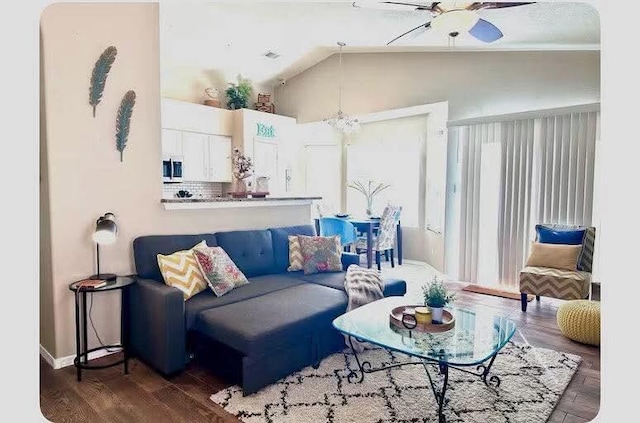 living room with vaulted ceiling, ceiling fan with notable chandelier, and dark hardwood / wood-style flooring