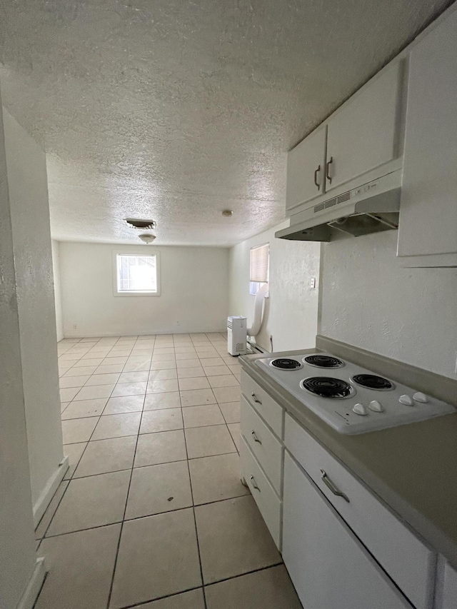 kitchen featuring a textured ceiling, white electric stovetop, white cabinets, and light tile patterned flooring