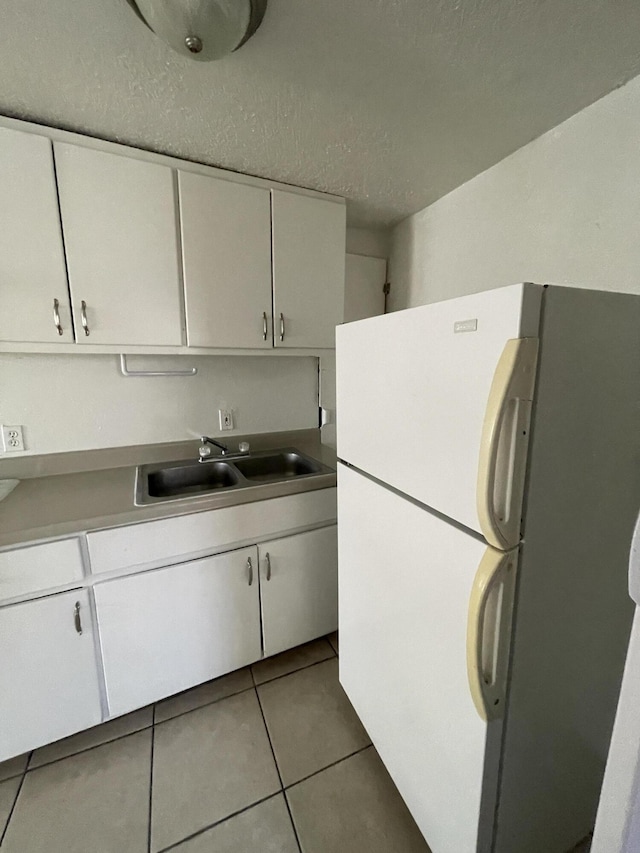 kitchen featuring tile patterned flooring, sink, white cabinetry, and white refrigerator