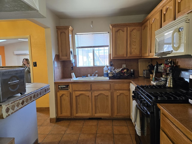 kitchen featuring light tile patterned flooring, sink, a wall unit AC, black gas range, and backsplash