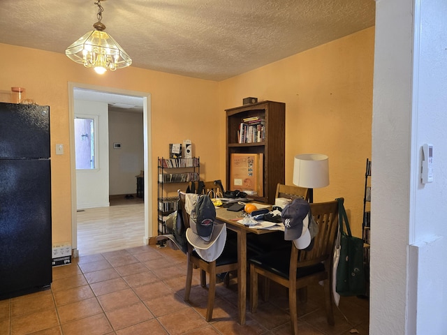 dining area with an inviting chandelier, tile patterned flooring, and a textured ceiling