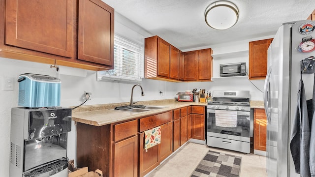 kitchen with light tile patterned floors, stainless steel appliances, a textured ceiling, and sink