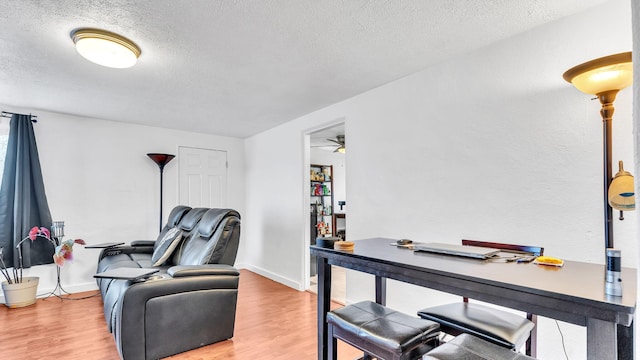 home office featuring hardwood / wood-style flooring, ceiling fan, and a textured ceiling