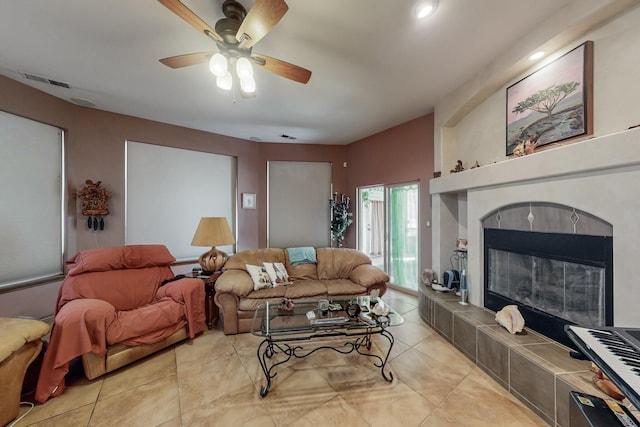 living room featuring a tile fireplace and ceiling fan