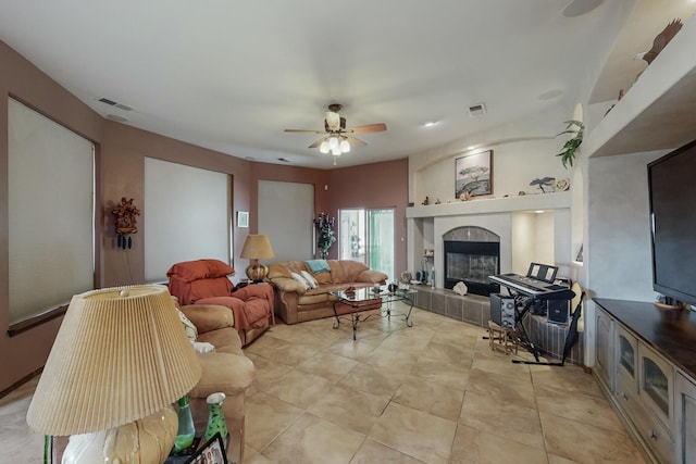 living room with ceiling fan and a tiled fireplace